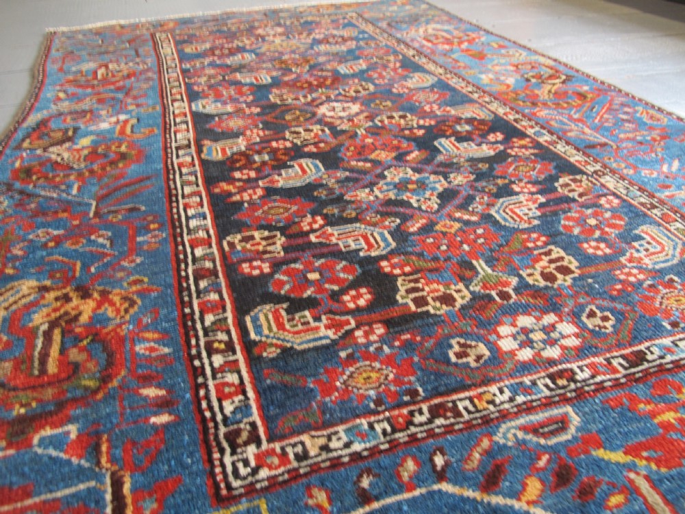 A late 19th-century hand-knotted Persian Hamadan wool rug featuring a dark navy central field surrounded by vibrant blue and red borders with intricate geometric floral motifs. View XXVI