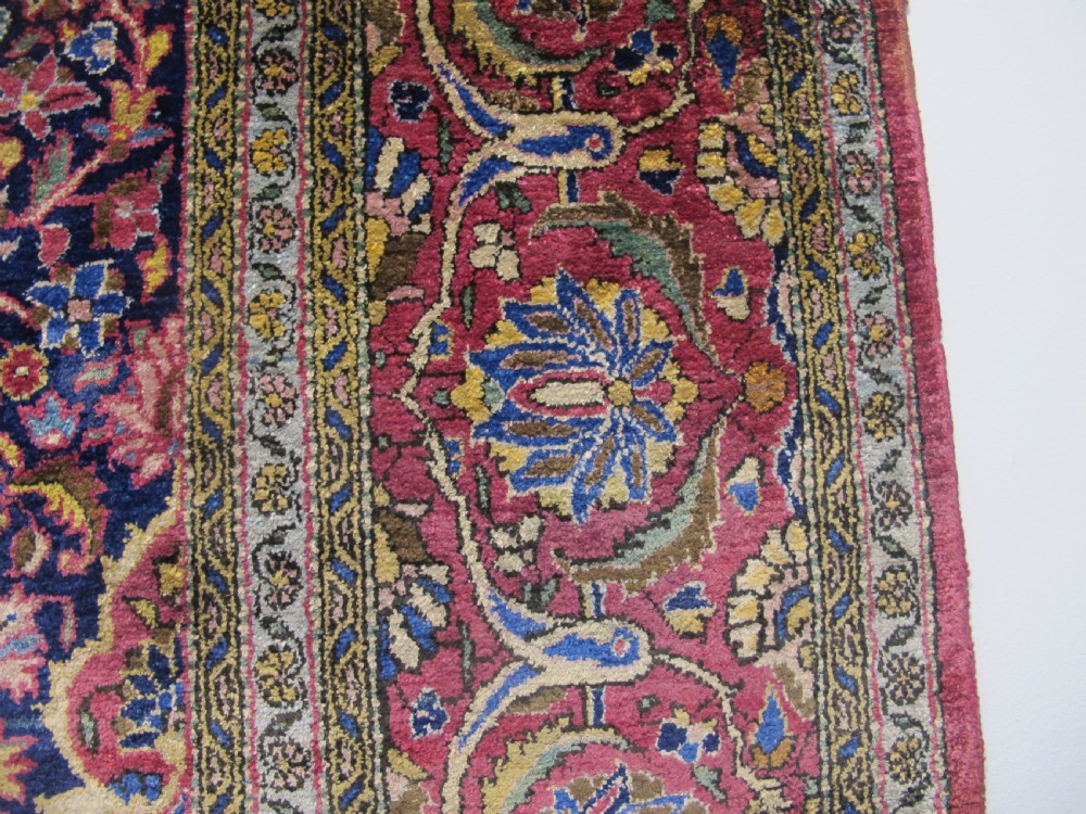 An antique central Persian silk Kashan rug featuring an intricate central medallion surrounded by floral motifs in crimson, navy blue, and gold tones. View VIII