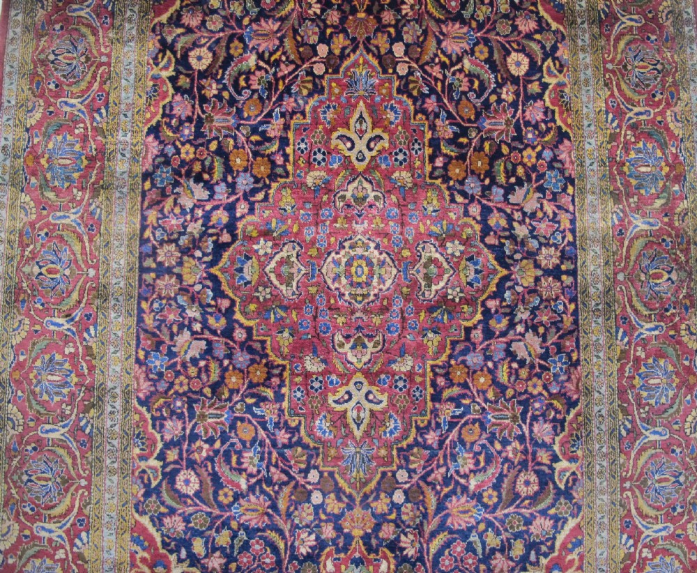 An antique central Persian silk Kashan rug featuring an intricate central medallion surrounded by floral motifs in crimson, navy blue, and gold tones. View XI