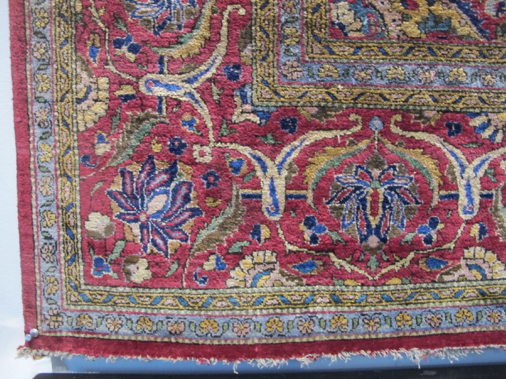 An antique central Persian silk Kashan rug featuring an intricate central medallion surrounded by floral motifs in crimson, navy blue, and gold tones. View XIV