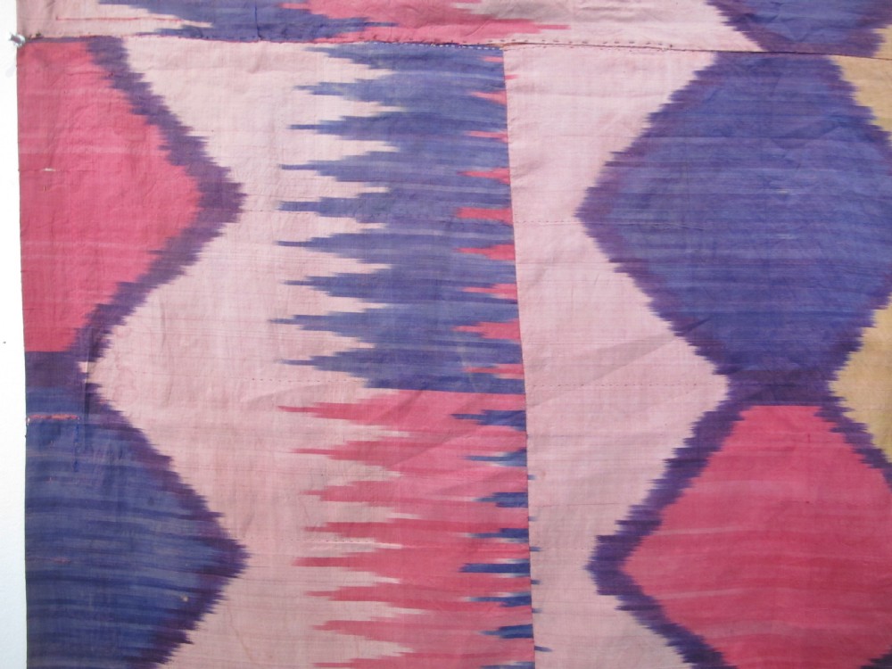 A large handwoven silk ikat textile panel from Uzbekistan featuring geometric diamond motifs and sawtooth patterns in pink, yellow, and purple. View VIII
