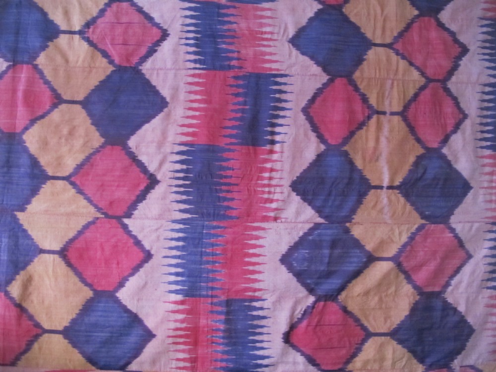 A large handwoven silk ikat textile panel from Uzbekistan featuring geometric diamond motifs and sawtooth patterns in pink, yellow, and purple. View XIII