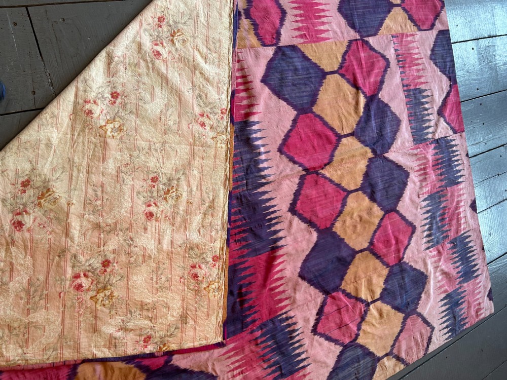 A large handwoven silk ikat textile panel from Uzbekistan featuring geometric diamond motifs and sawtooth patterns in pink, yellow, and purple. View XVI