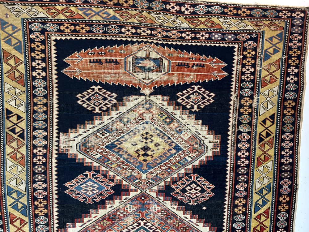 A rectangular hand-knotted wool rug displaying four diamond medallions along a navy central field surrounded by multi-tiered geometric borders. View II