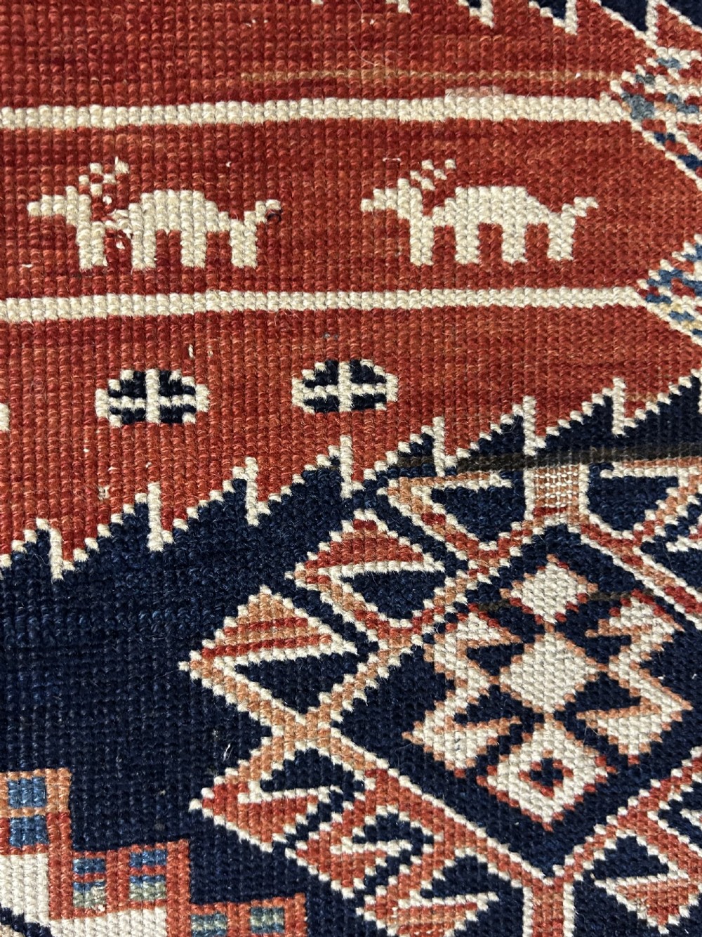 A rectangular hand-knotted wool rug displaying four diamond medallions along a navy central field surrounded by multi-tiered geometric borders. View XII