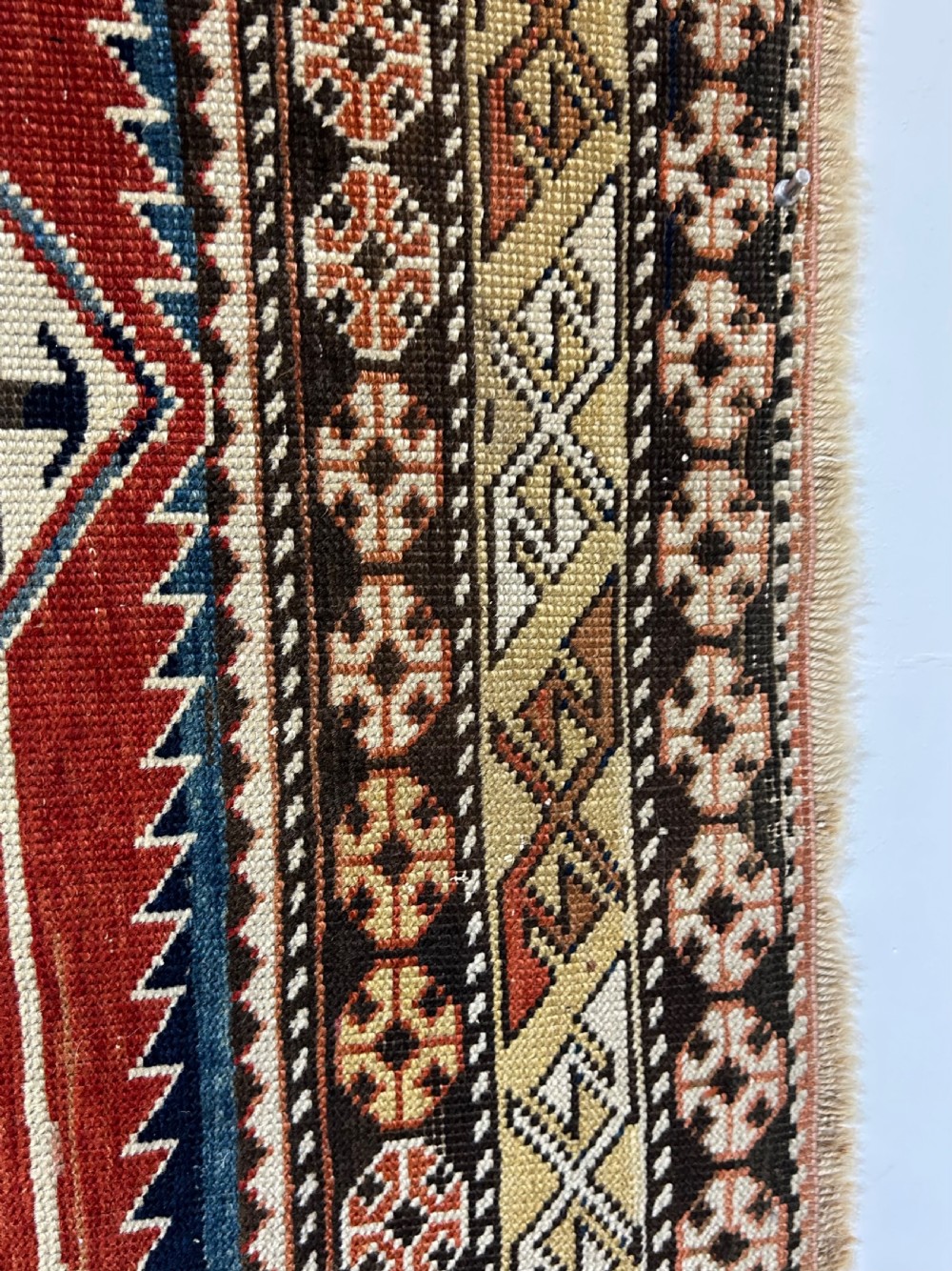 A rectangular hand-knotted wool rug displaying four diamond medallions along a navy central field surrounded by multi-tiered geometric borders. View XV