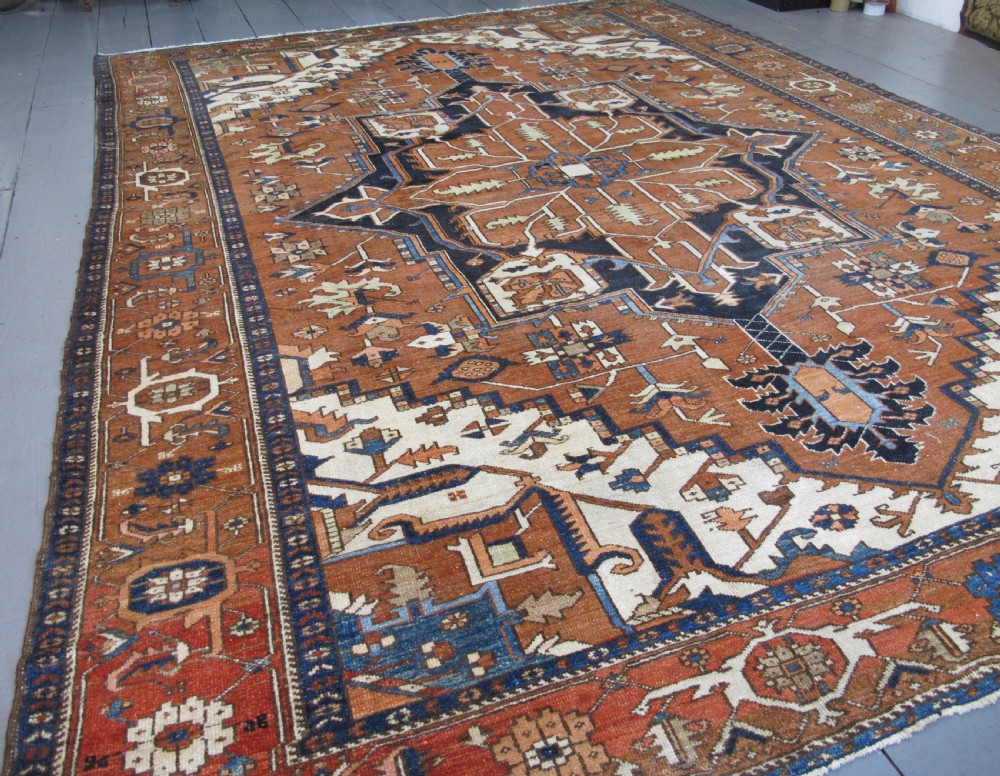 A large 19th-century antique Persian Serapi wool carpet featuring a bold geometric central medallion in navy blue and terracotta on an ivory field with wide decorative borders. View II