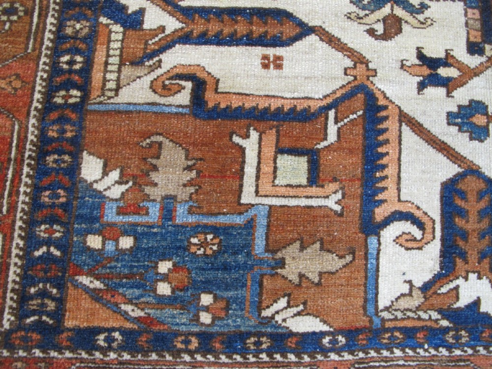 A large 19th-century antique Persian Serapi wool carpet featuring a bold geometric central medallion in navy blue and terracotta on an ivory field with wide decorative borders. View V
