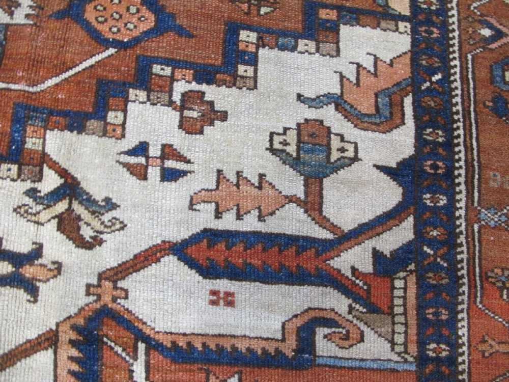 A large 19th-century antique Persian Serapi wool carpet featuring a bold geometric central medallion in navy blue and terracotta on an ivory field with wide decorative borders. View VI
