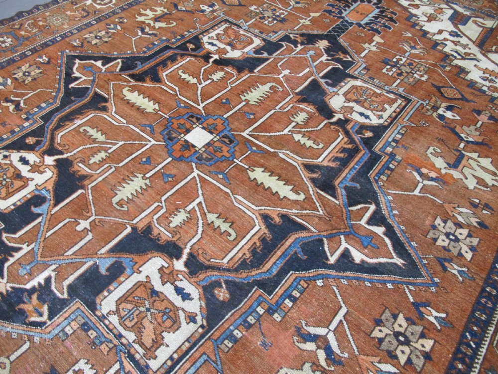 A large 19th-century antique Persian Serapi wool carpet featuring a bold geometric central medallion in navy blue and terracotta on an ivory field with wide decorative borders. View VIII