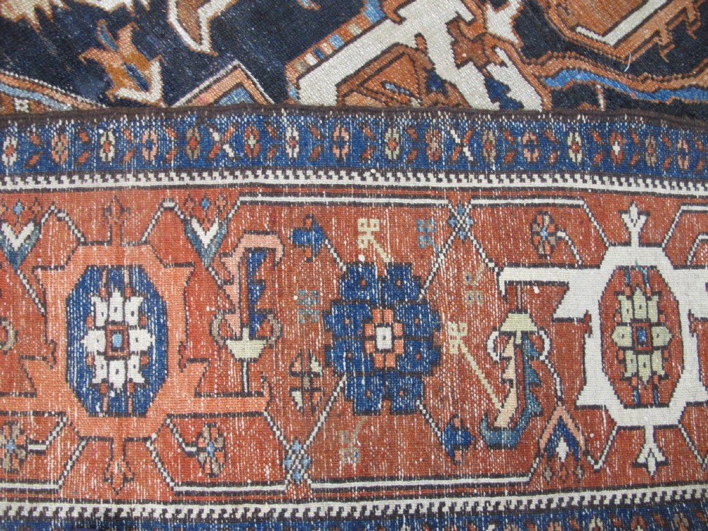 A large 19th-century antique Persian Serapi wool carpet featuring a bold geometric central medallion in navy blue and terracotta on an ivory field with wide decorative borders. View XIII