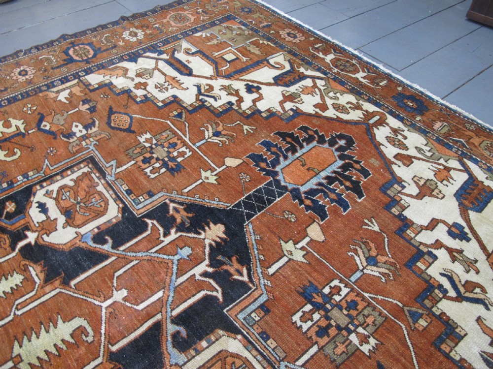 A large 19th-century antique Persian Serapi wool carpet featuring a bold geometric central medallion in navy blue and terracotta on an ivory field with wide decorative borders. View XIV