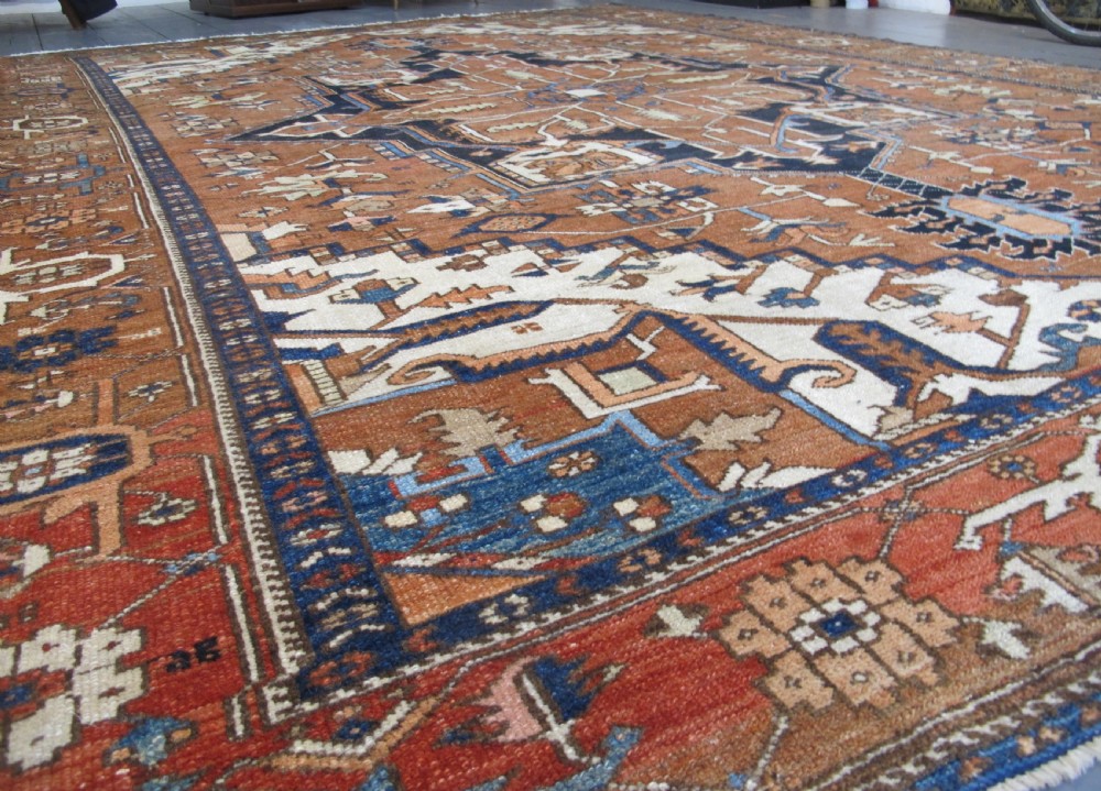 A large 19th-century antique Persian Serapi wool carpet featuring a bold geometric central medallion in navy blue and terracotta on an ivory field with wide decorative borders. View XV