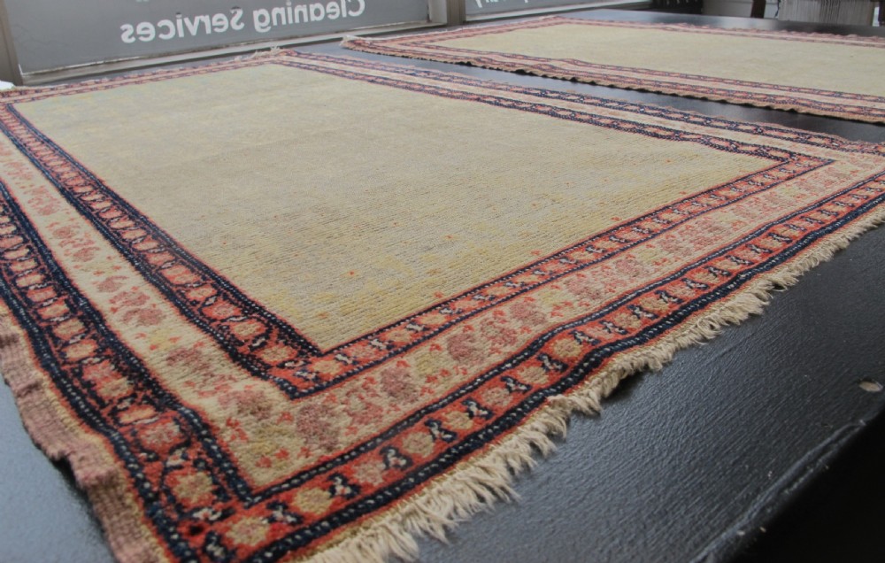 A pair of late nineteenth-century Persian Senneh hand-knotted wool rugs featuring pale cream central fields and multi-stripe red borders. View II