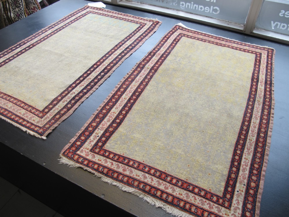 A pair of late nineteenth-century Persian Senneh hand-knotted wool rugs featuring pale cream central fields and multi-stripe red borders. View III