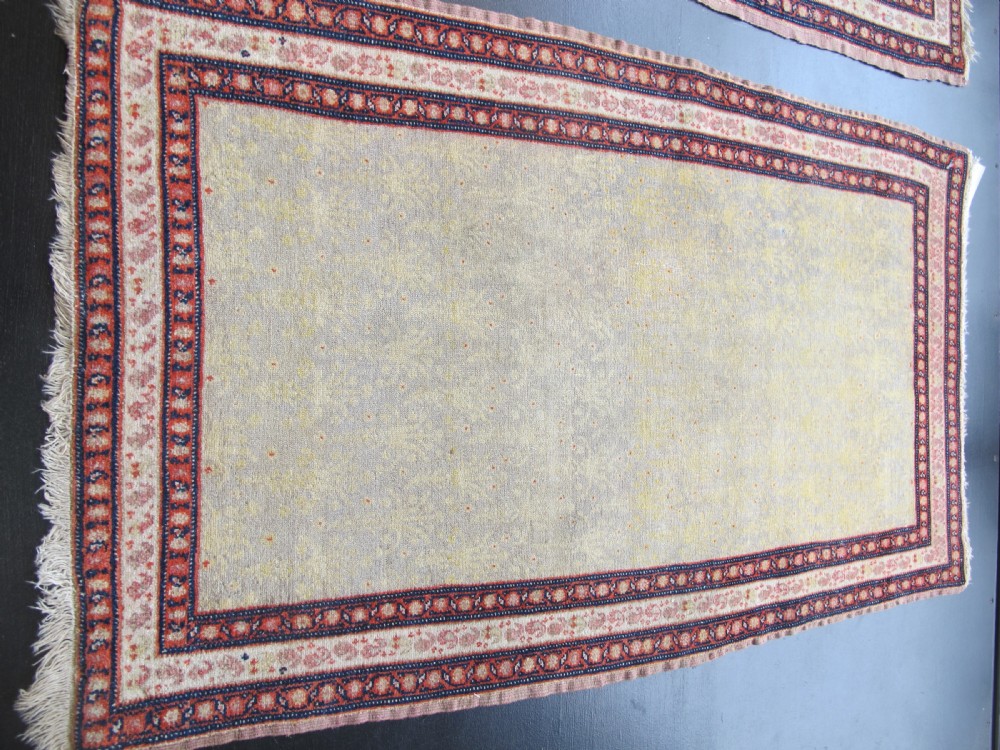 A pair of late nineteenth-century Persian Senneh hand-knotted wool rugs featuring pale cream central fields and multi-stripe red borders. View IV