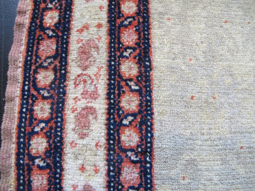 A pair of late nineteenth-century Persian Senneh hand-knotted wool rugs featuring pale cream central fields and multi-stripe red borders. View VIII