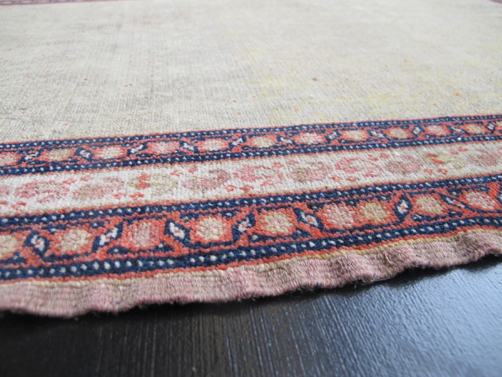 A pair of late nineteenth-century Persian Senneh hand-knotted wool rugs featuring pale cream central fields and multi-stripe red borders. View IX