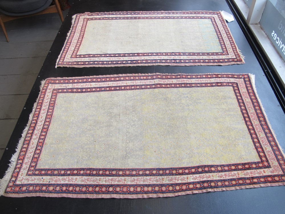 A pair of late nineteenth-century Persian Senneh hand-knotted wool rugs featuring pale cream central fields and multi-stripe red borders. View X
