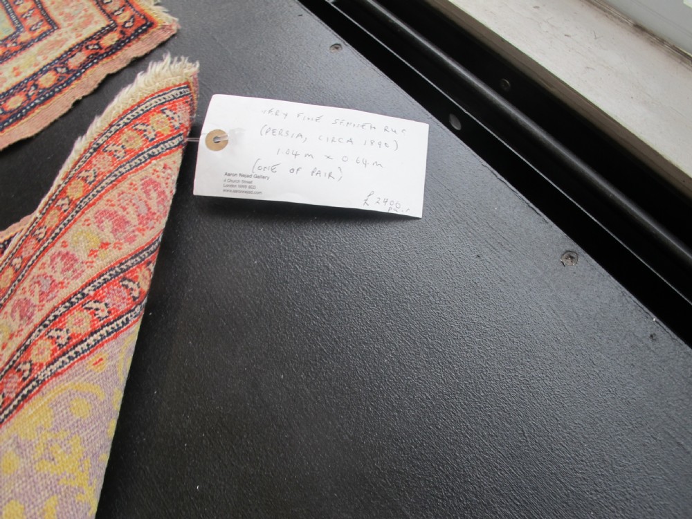 A pair of late nineteenth-century Persian Senneh hand-knotted wool rugs featuring pale cream central fields and multi-stripe red borders. View XII