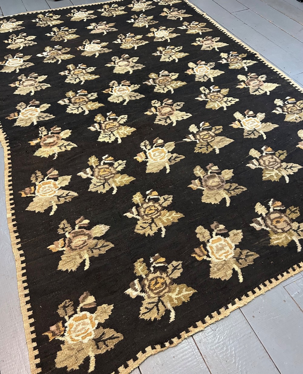 A large flat-woven Ukrainian wool kilim featuring a dark brown background decorated with repeating beige and mustard floral motifs. View II