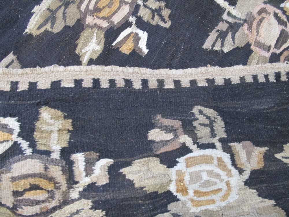 A large flat-woven Ukrainian wool kilim featuring a dark brown background decorated with repeating beige and mustard floral motifs. View XIV