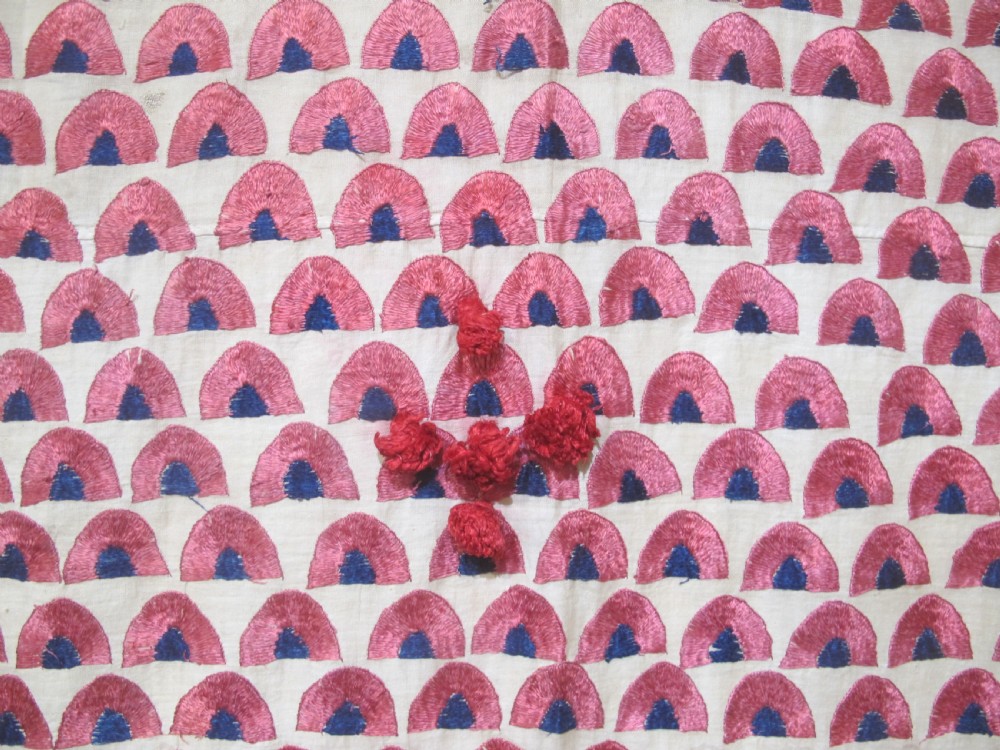 An antique rectangular Sindh embroidered textile featuring a repeating red arched pattern on a beige ground with decorative borders and tassels. View IV