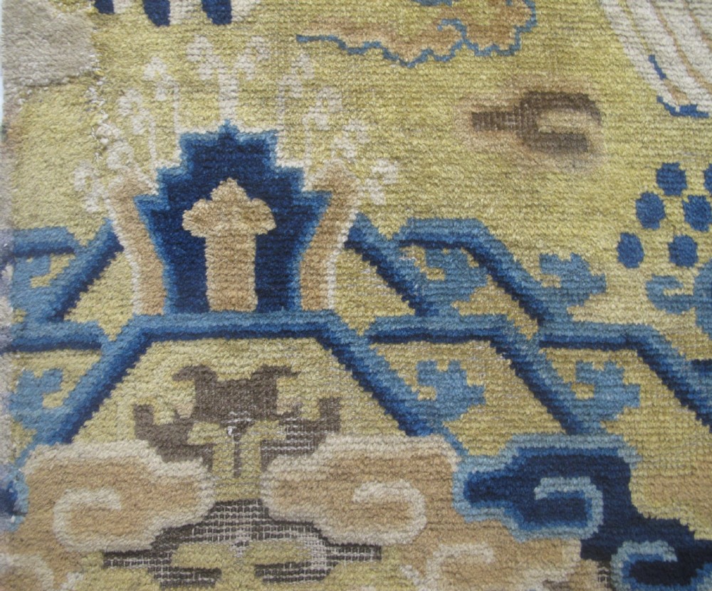 A vertical mid-19th-century Northern Chinese Ningxia pillar rug featuring indigo dragon claws, clouds, and wave motifs woven onto a yellow wool field. View IV