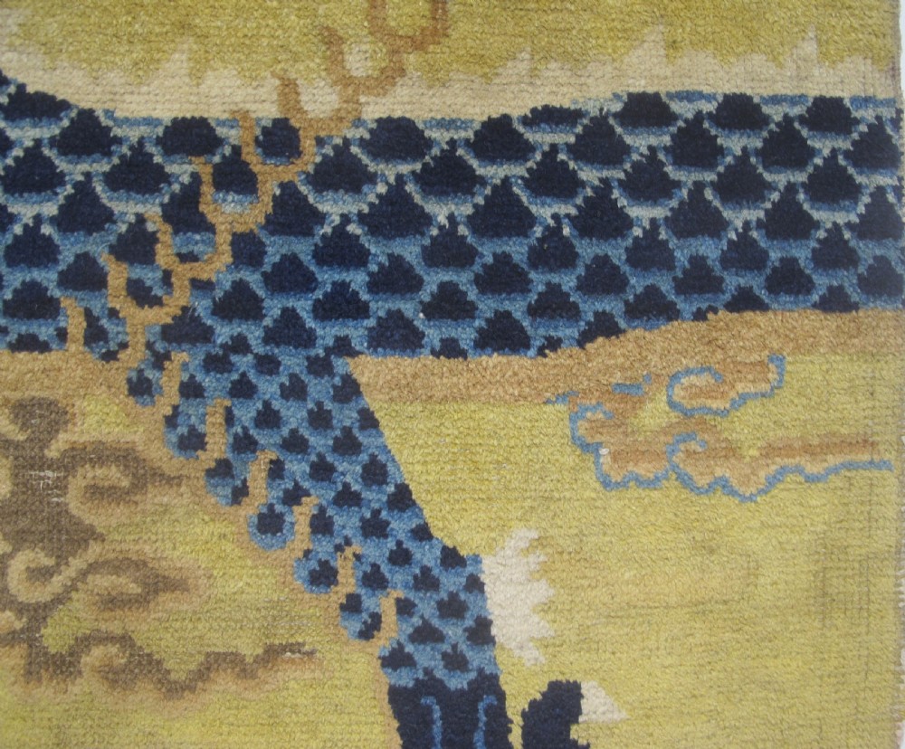 A vertical mid-19th-century Northern Chinese Ningxia pillar rug featuring indigo dragon claws, clouds, and wave motifs woven onto a yellow wool field. View IX