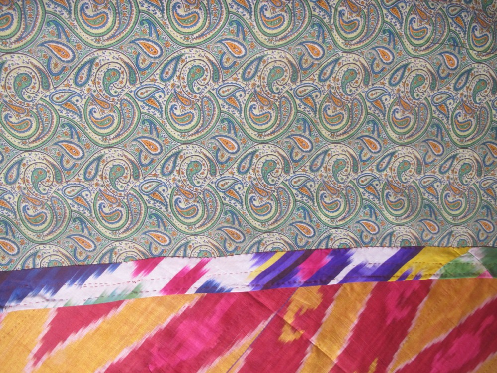 A rectangular handwoven silk ikat textile panel featuring large geometric chevron and diamond patterns in red, yellow, and magenta hues. View IV