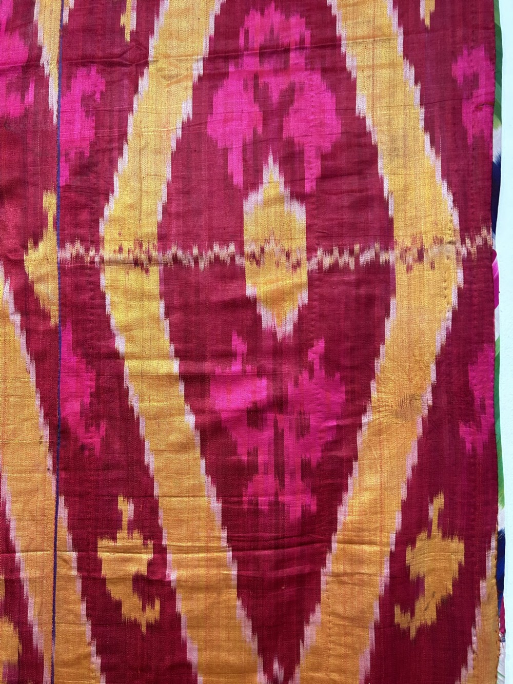 A rectangular handwoven silk ikat textile panel featuring large geometric chevron and diamond patterns in red, yellow, and magenta hues. View VIII