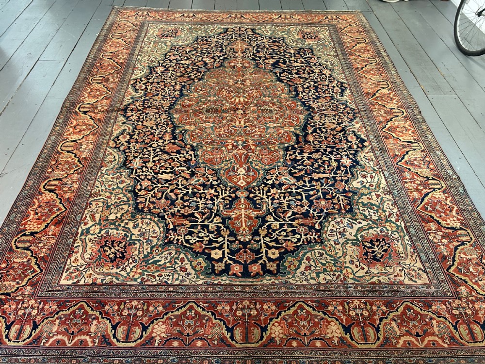 An antique Persian Fereghan carpet featuring an intricate central medallion on a dark navy field surrounded by detailed floral spandrels and terracotta borders.