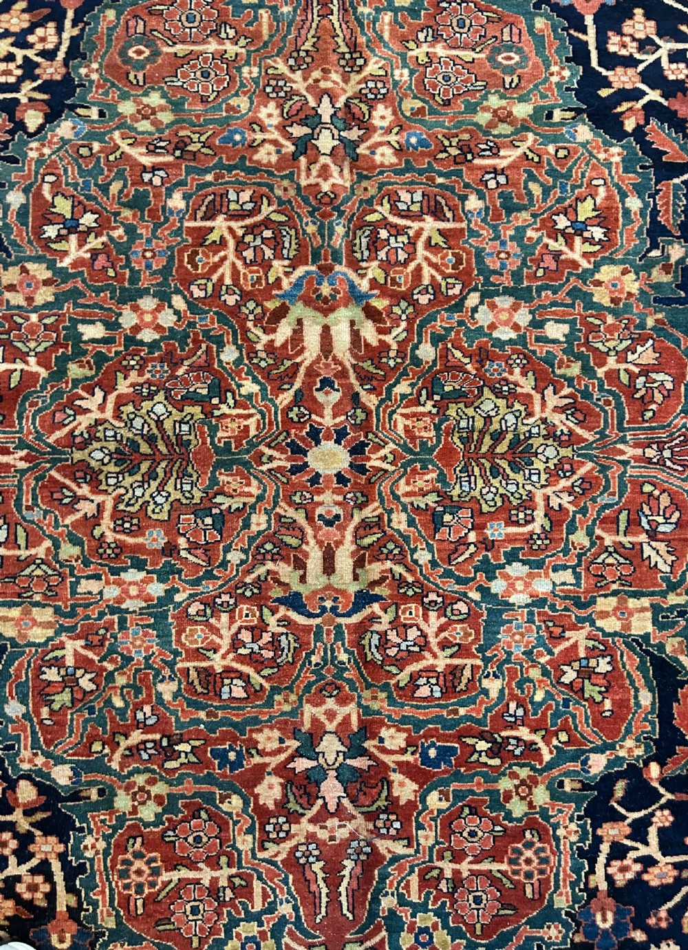 An antique Persian Fereghan carpet featuring an intricate central medallion on a dark navy field surrounded by detailed floral spandrels and terracotta borders. View IX