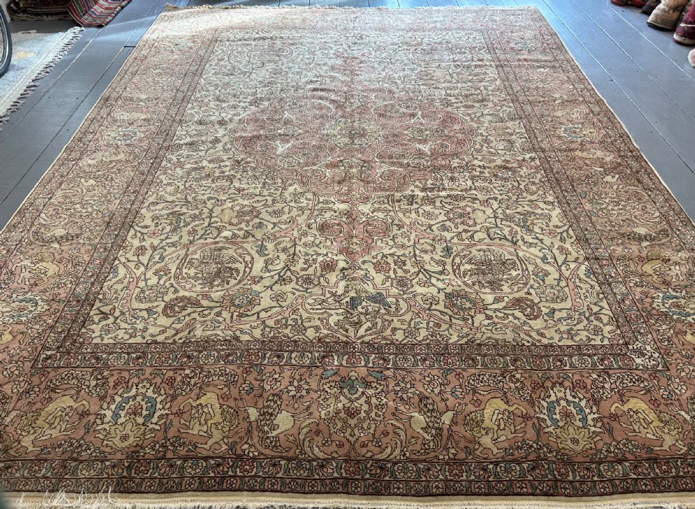 A large hand-knotted Persian Tabriz wool carpet featuring a central cream and terracotta medallion surrounded by intricate floral arabesques and border detail.