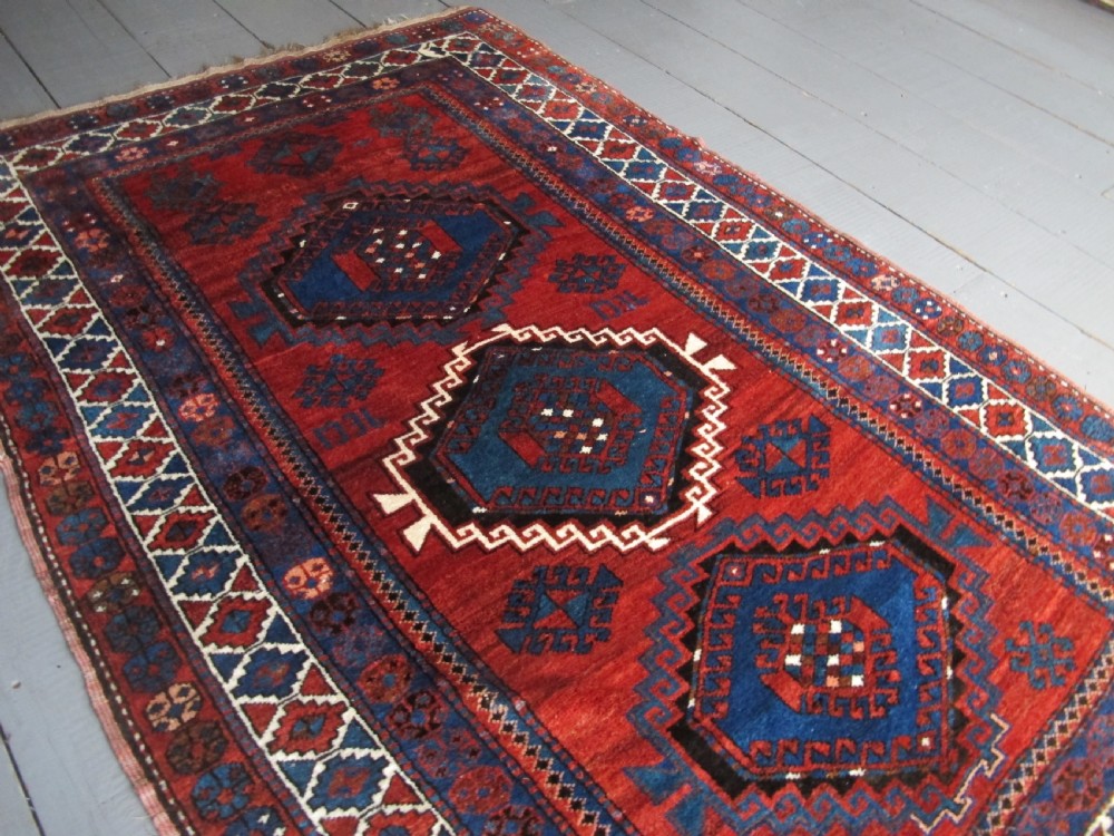 A hand-knotted Caucasian Kazak wool rug featuring three central geometric diamond medallions on a red field framed by patterned borders. View II