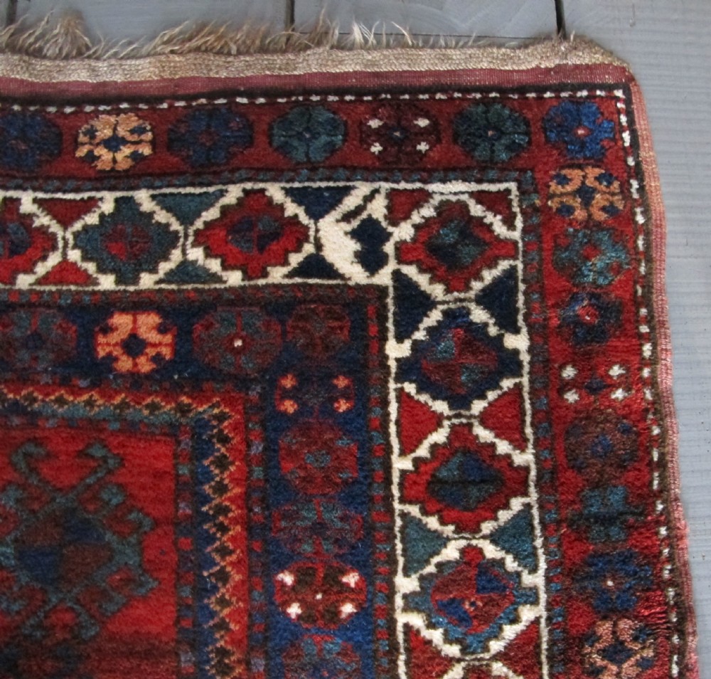 A hand-knotted Caucasian Kazak wool rug featuring three central geometric diamond medallions on a red field framed by patterned borders. View VI