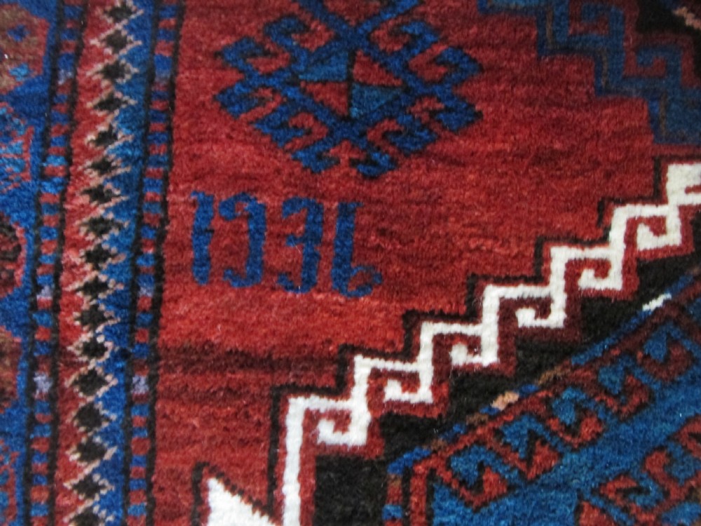 A hand-knotted Caucasian Kazak wool rug featuring three central geometric diamond medallions on a red field framed by patterned borders. View XI