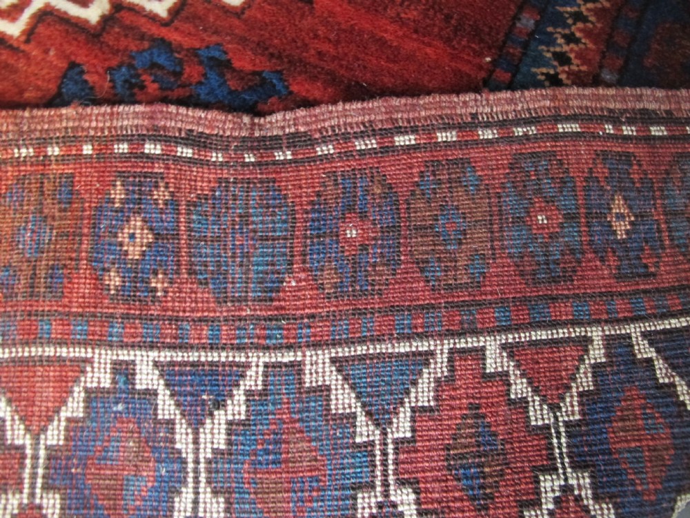 A hand-knotted Caucasian Kazak wool rug featuring three central geometric diamond medallions on a red field framed by patterned borders. View XIII