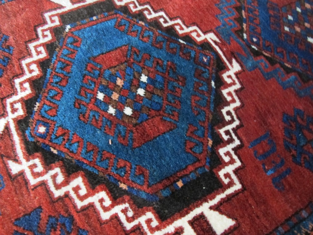 A hand-knotted Caucasian Kazak wool rug featuring three central geometric diamond medallions on a red field framed by patterned borders. View XIV