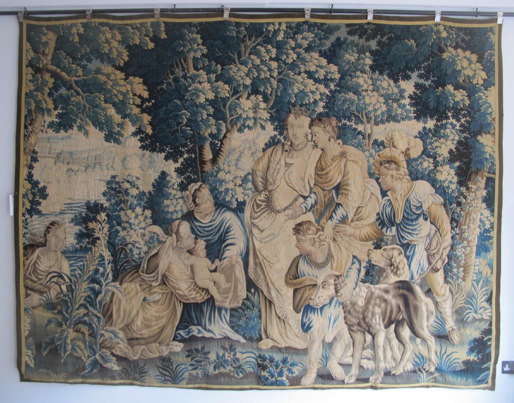 A large 17th-century woven Aubusson tapestry displaying a biblical scene with figures, hounds, and foliage in shades of blue, cream, and green.