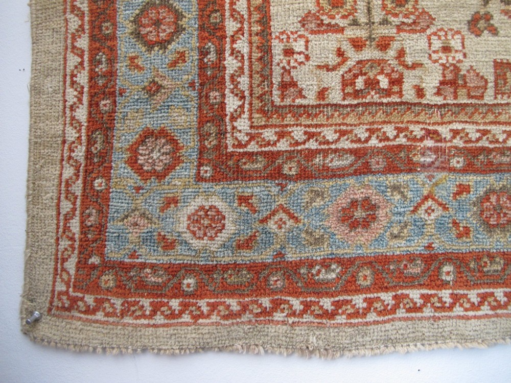 An antique Persian Ziegler wool rug featuring a repeating soft terracotta and light blue floral pattern across an ivory field, bordered by a decorative floral band. View VII