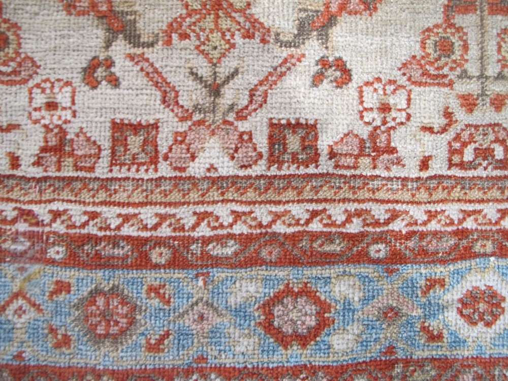An antique Persian Ziegler wool rug featuring a repeating soft terracotta and light blue floral pattern across an ivory field, bordered by a decorative floral band. View VIII