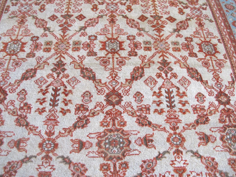 An antique Persian Ziegler wool rug featuring a repeating soft terracotta and light blue floral pattern across an ivory field, bordered by a decorative floral band. View XI