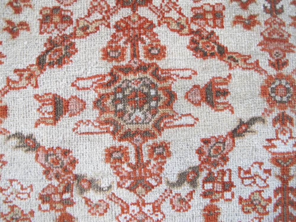 An antique Persian Ziegler wool rug featuring a repeating soft terracotta and light blue floral pattern across an ivory field, bordered by a decorative floral band. View XII