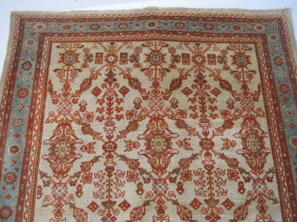 An antique Persian Ziegler wool rug featuring a repeating soft terracotta and light blue floral pattern across an ivory field, bordered by a decorative floral band. View XIII