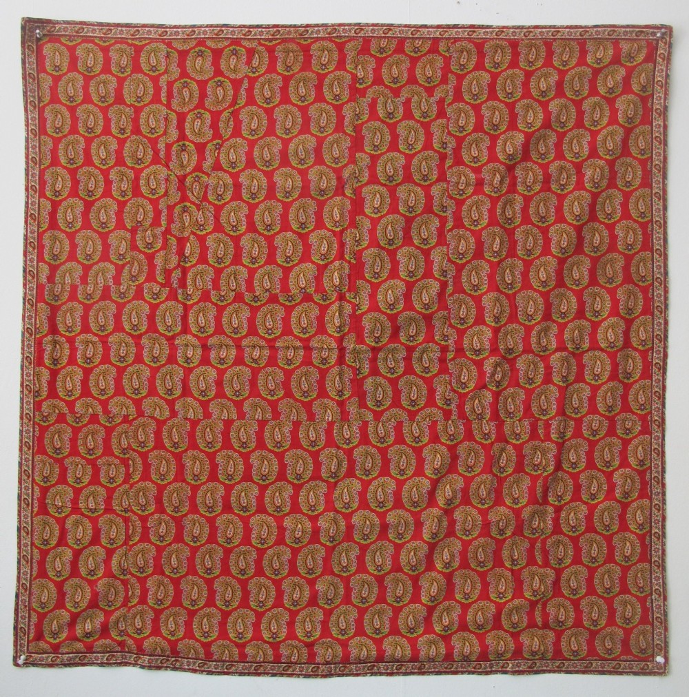 A square late nineteenth-century Indian cotton blockprint panel featuring a dense red, yellow, and green paisley pattern within a thin border.