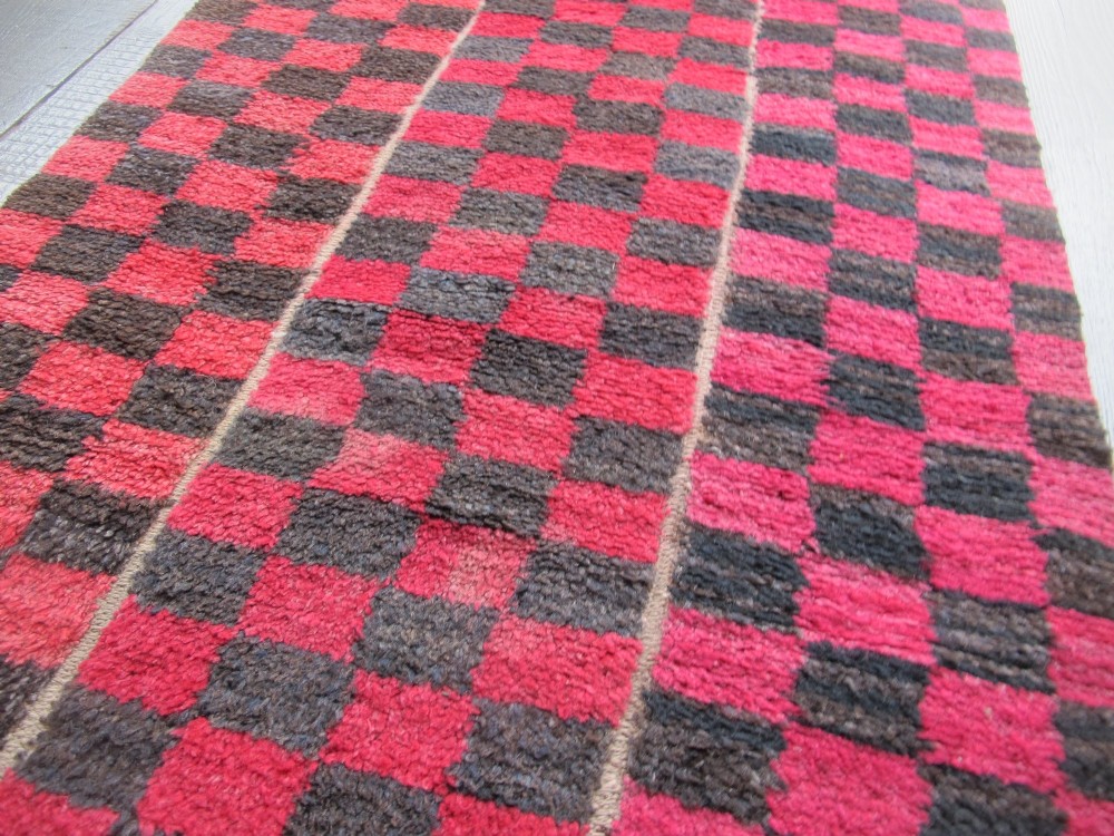 An antique Tibetan wool meditation rug featuring a three-panel chequerboard pattern in pink and dark grey. View III