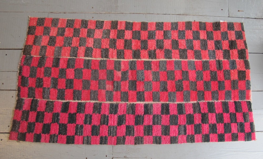 An antique Tibetan wool meditation rug featuring a three-panel chequerboard pattern in pink and dark grey. View IV