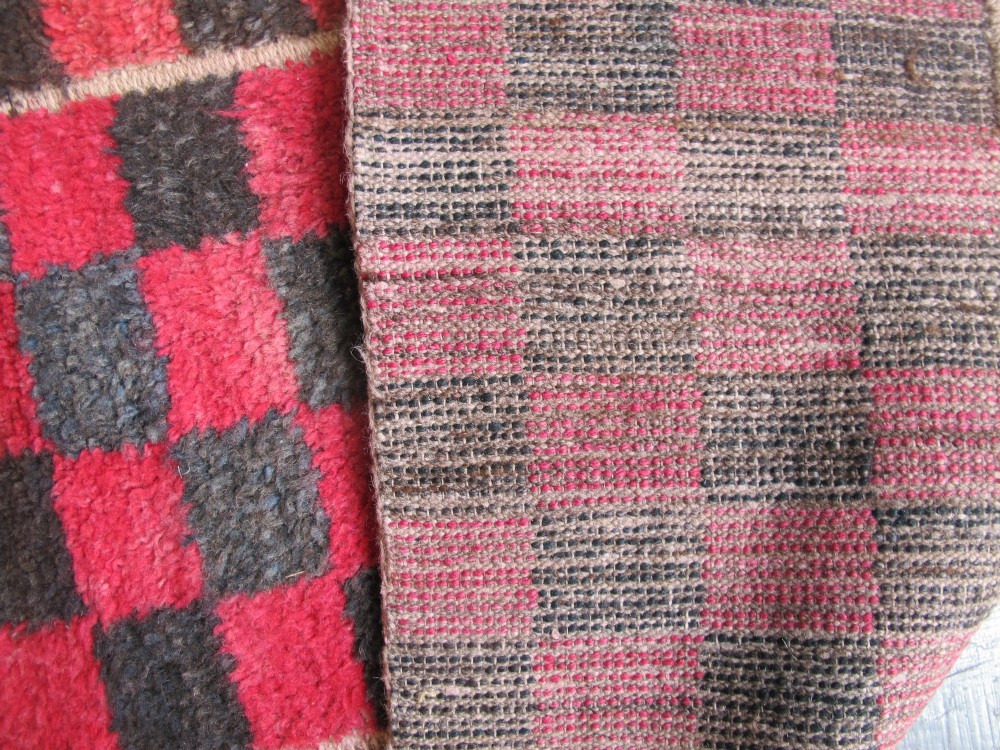 An antique Tibetan wool meditation rug featuring a three-panel chequerboard pattern in pink and dark grey. View V