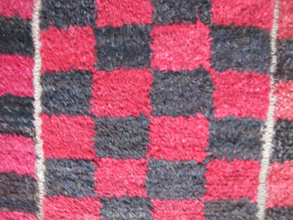 An antique Tibetan wool meditation rug featuring a three-panel chequerboard pattern in pink and dark grey. View VII